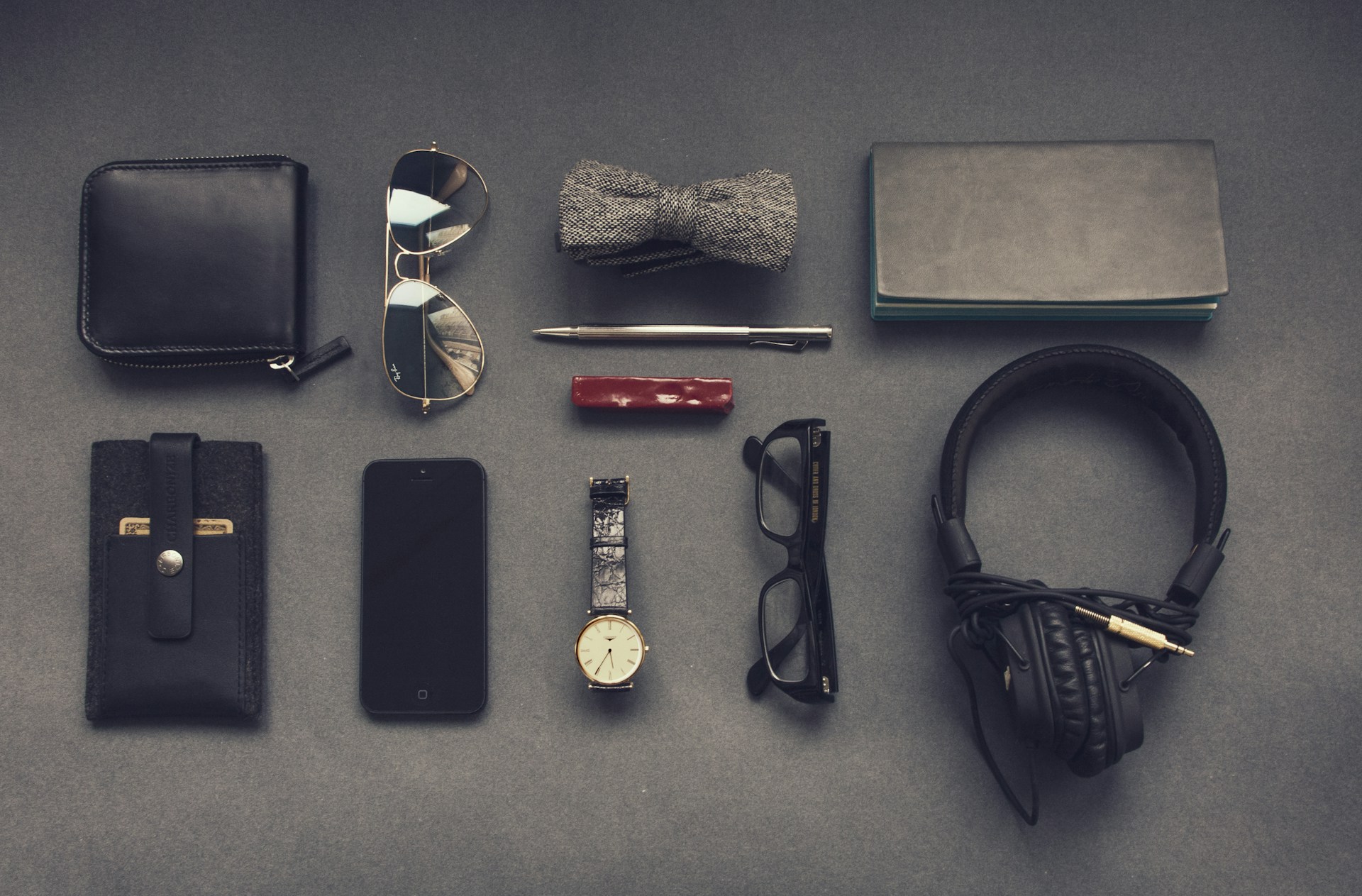 Flat lay of essential Everyday Carry (EDC) gear, including a phone, wallet, flashlight, multi-tool, key organizer, etc. neatly arranged on a wooden surface.