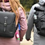 Two people walking outdoors wearing different types of EDC backpacks—one sleek and minimalist, the other rugged and tactical—demonstrating versatility in everyday carry bag choices