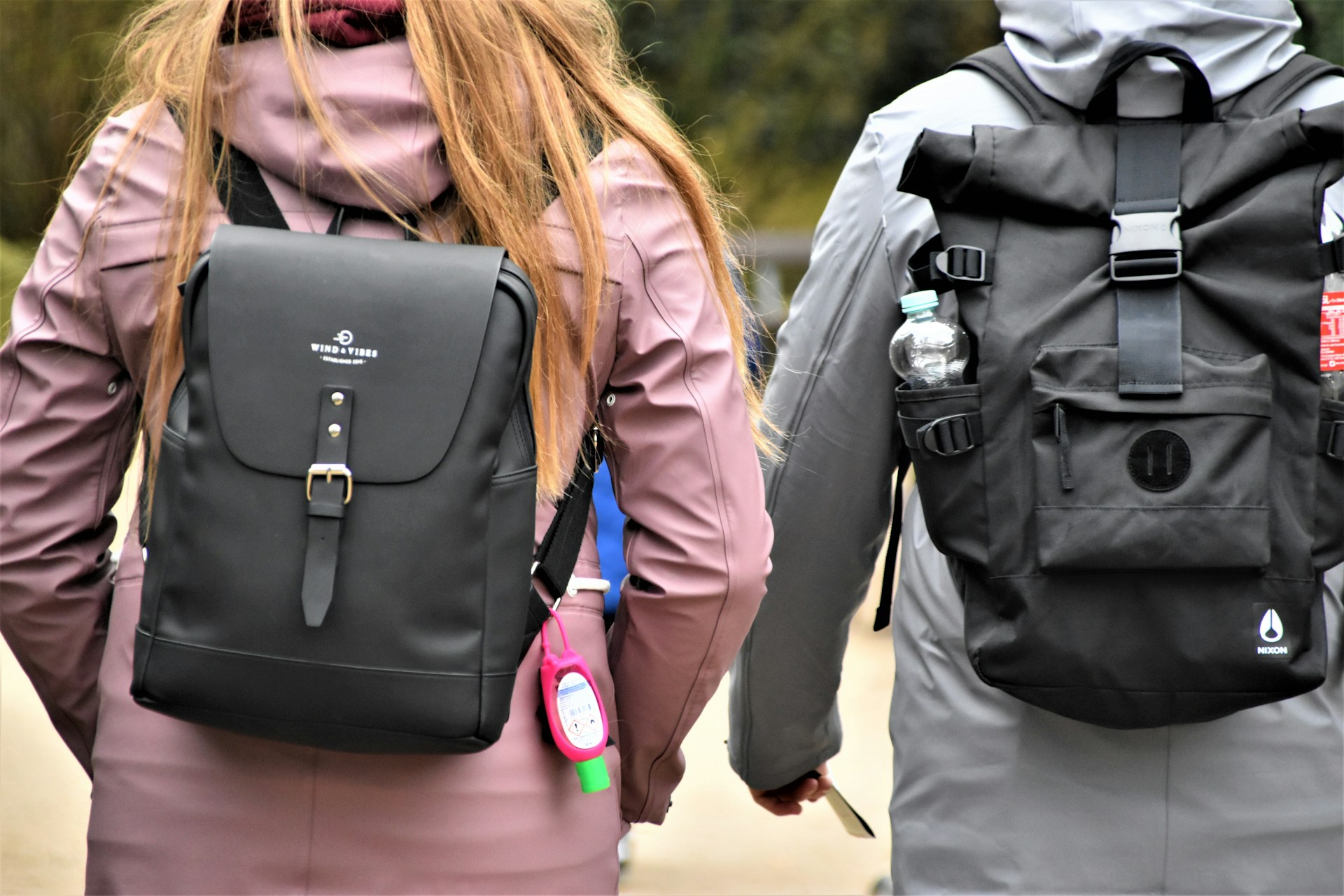 Two people walking outdoors wearing different types of EDC backpacks—one sleek and minimalist, the other rugged and tactical—demonstrating versatility in everyday carry bag choices